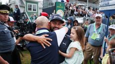 JJ Spaun holds his daughter and hugs his coach after winning the US Open while a TV camera films in the background