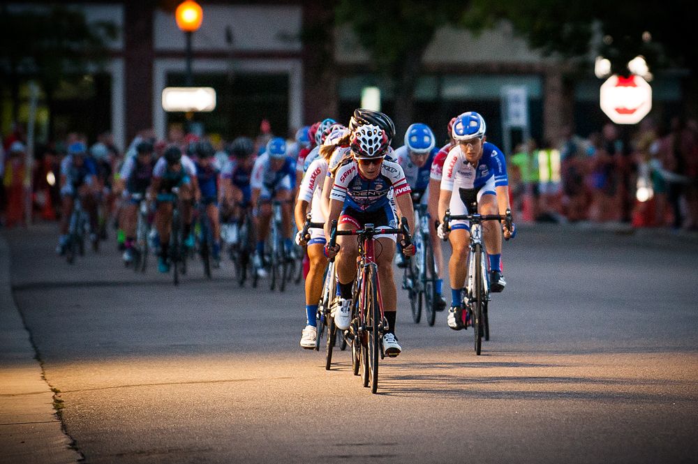 The women's field winds its way through the streets of downtown Littleton as the sun begins to set.
