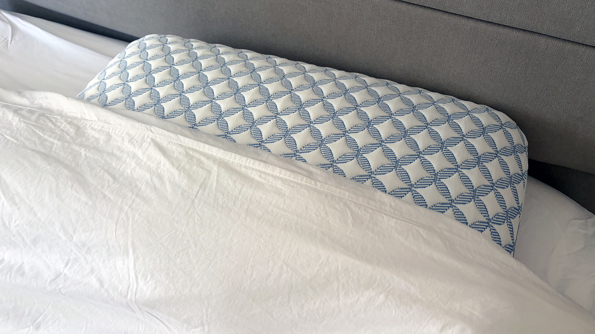 The Helix Cooling Memory Foam pillow at the head of the bed in our reviewer's bedroom, partly tucked under a cover