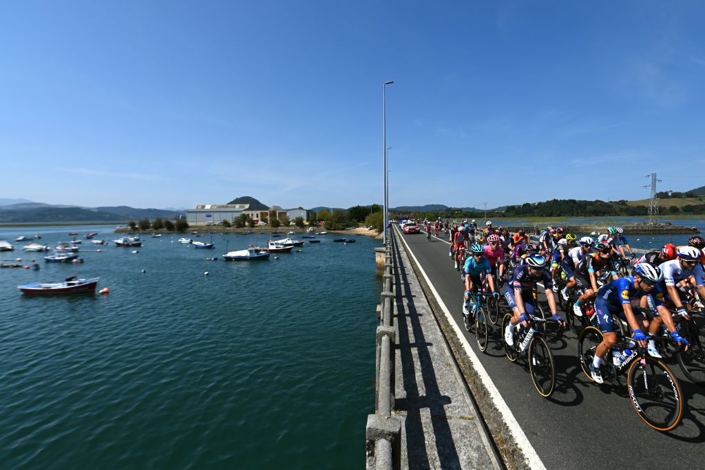 SANTA CRUZ DE BEZANA SPAIN AUGUST 31 A general view of the Peloton passing through a bridge in Santoa Village during the 76th Tour of Spain 2021 Stage 16 a 180km stage from Laredo to Santa Cruz de Bezana lavuelta LaVuelta21 on August 31 2021 in Santa Cruz de Bezana Spain Photo by Stuart FranklinGetty Images