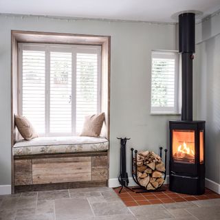 window seat beside a wood burning stove in a corner with limestone tiled floor