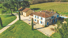A white house with blue shutters set amid the rolling hills of Gers, Gascony.