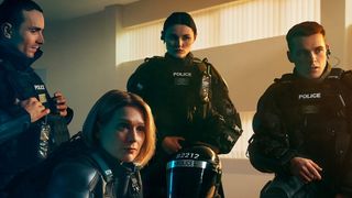 Four of the main characters from Blue Lights season 2 sitting around in the station in Belfast in full police uniform (from left to right): Stevie Neil (Martin McCann), Grace Ellis (Siân Brooke), Annie Conlon (Katherine Devlin) and Tommy Foster (Nathan Braniff)