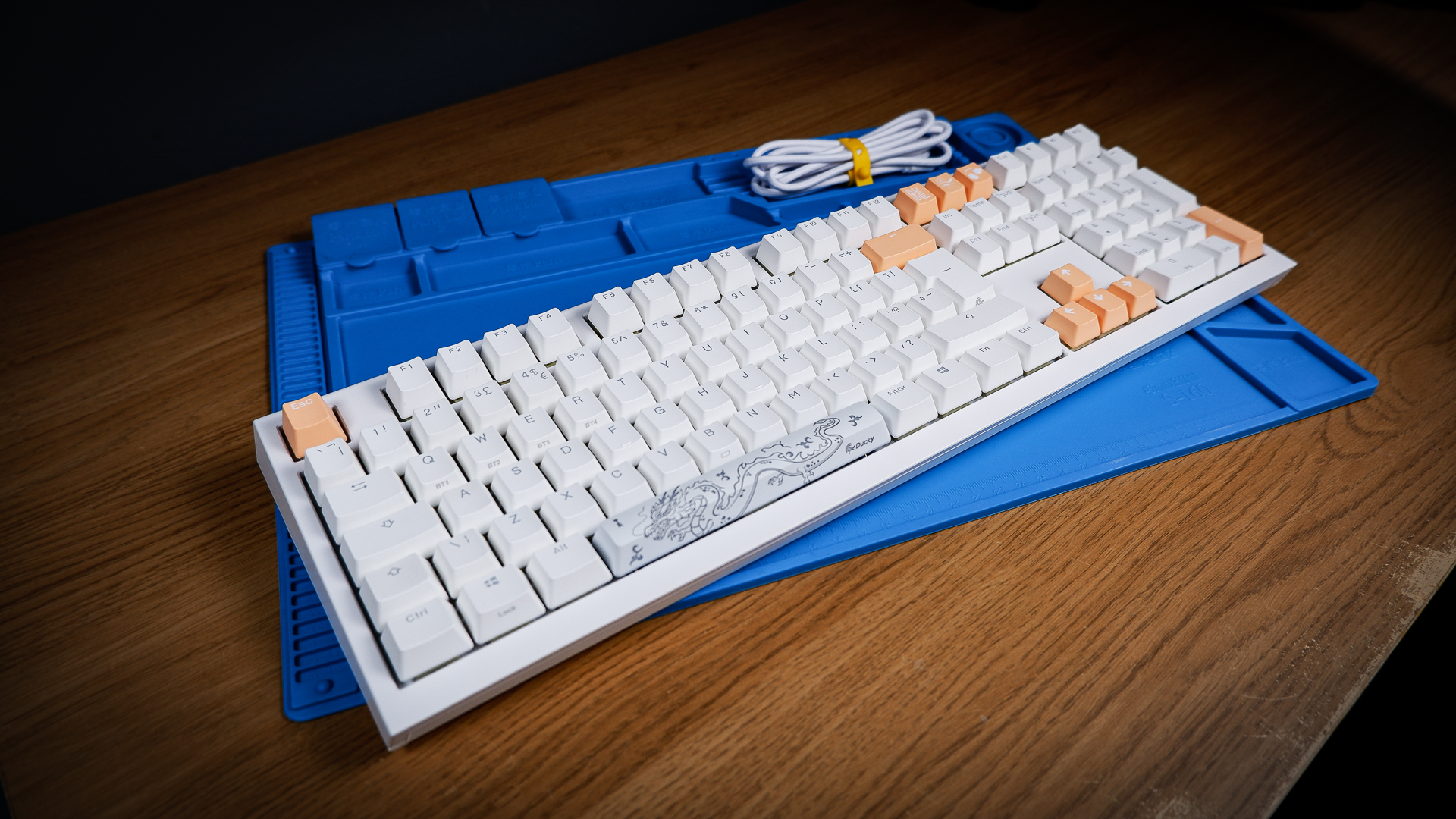 The Ducky One X induction gaming keyboard on a blue mat on a desk, with keycaps removed.