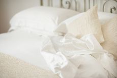 white bedding with pillows and a sheet, to illustrate how to get rid of dust mites