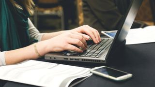 Bästa gratis PDF-editor: En kvinna som sitter och arbetar på en laptop.