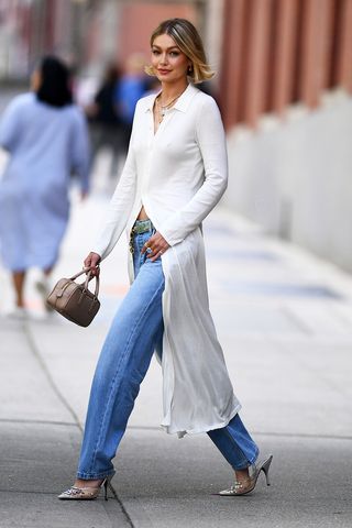 Gigi Hadid wearing a white top, jeans, sunglasses, and necklaces