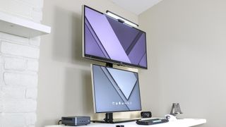 An ultrawide monitor stacked on top of a 27-inch, 16:9 monitor on a desk