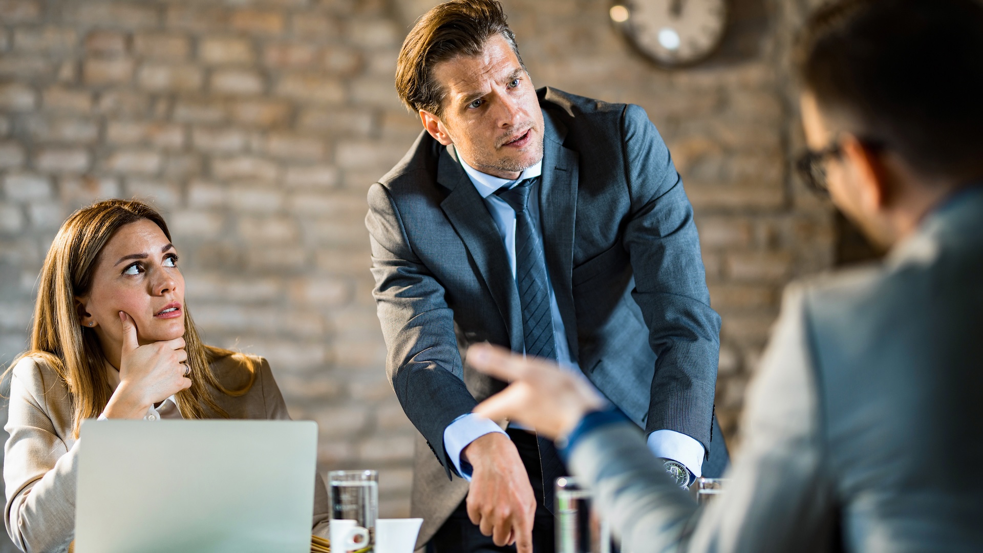 a photo of a man in a suit yelling at two other people in the office