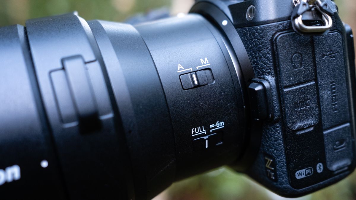 Close up photos of the Nikkor Z 180-600mm f/5.6-6.3 VR mounted on a tripod with foliage in the background