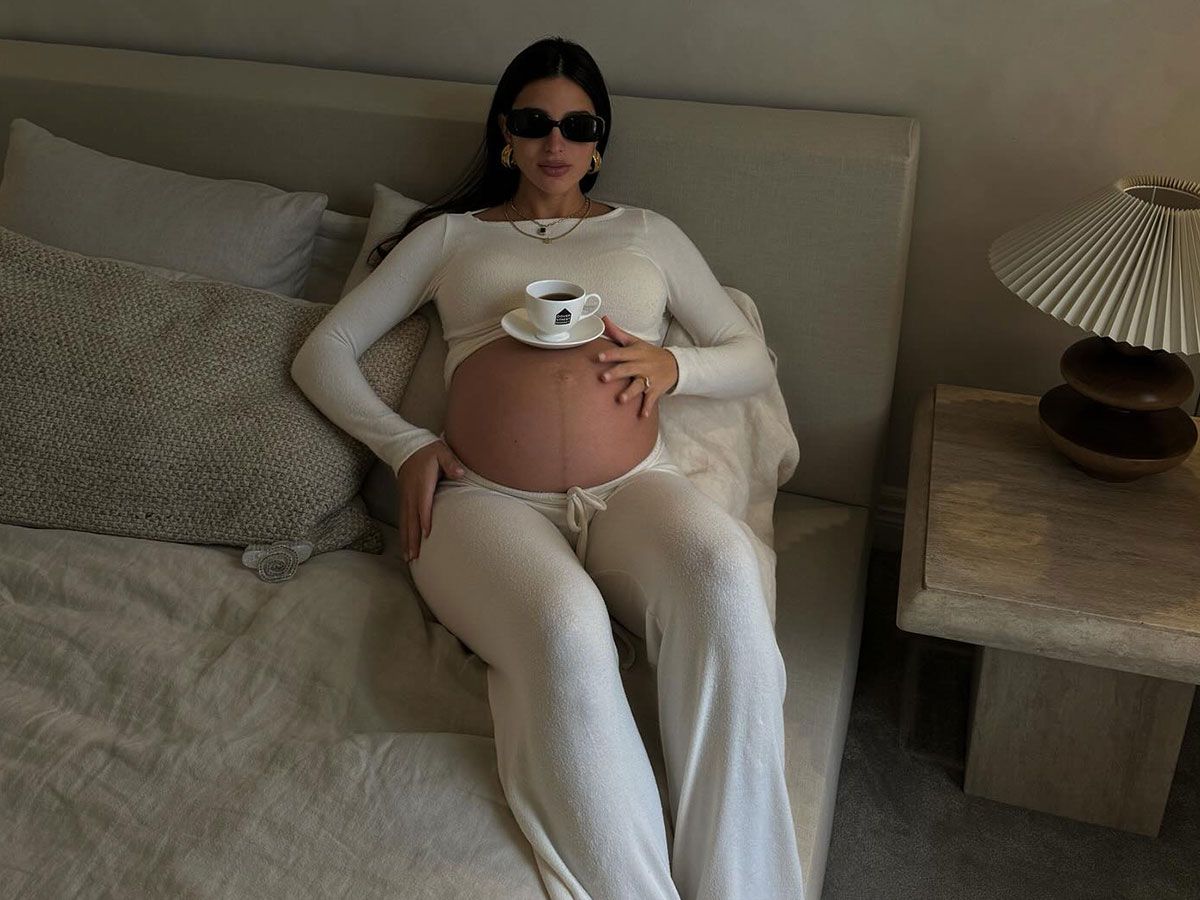 @bettinalooney wearing a matching set and balancing a cup of coffee on her pregnant belly.