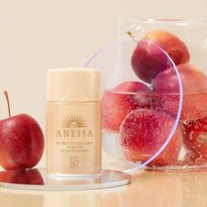 Anessa Perfect sunscreen mild milk next to a bowl of red apples