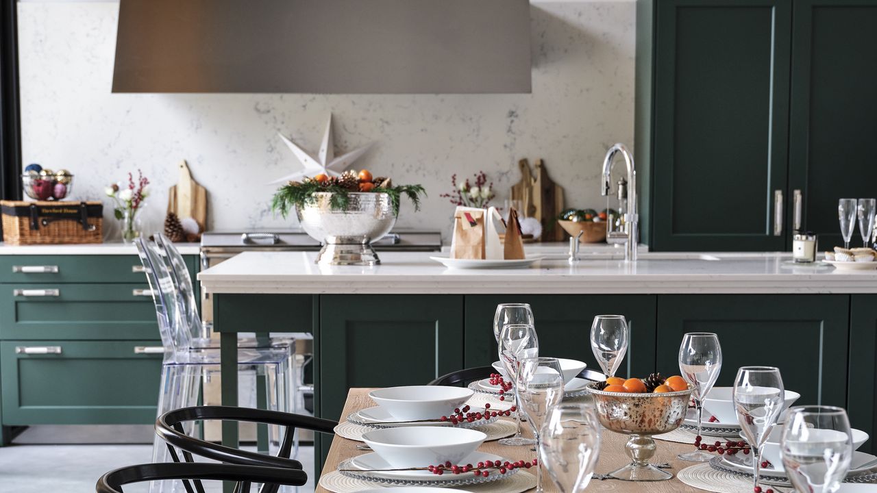 Green kitchen with island and open plan layout with dining table.