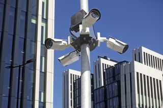Four surveillance cameras on top of a white pole somewhere in London