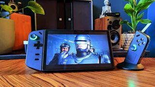 Lenovo Legion Go handheld sitting on woodgrain table with right controller detached and Robocop on screen