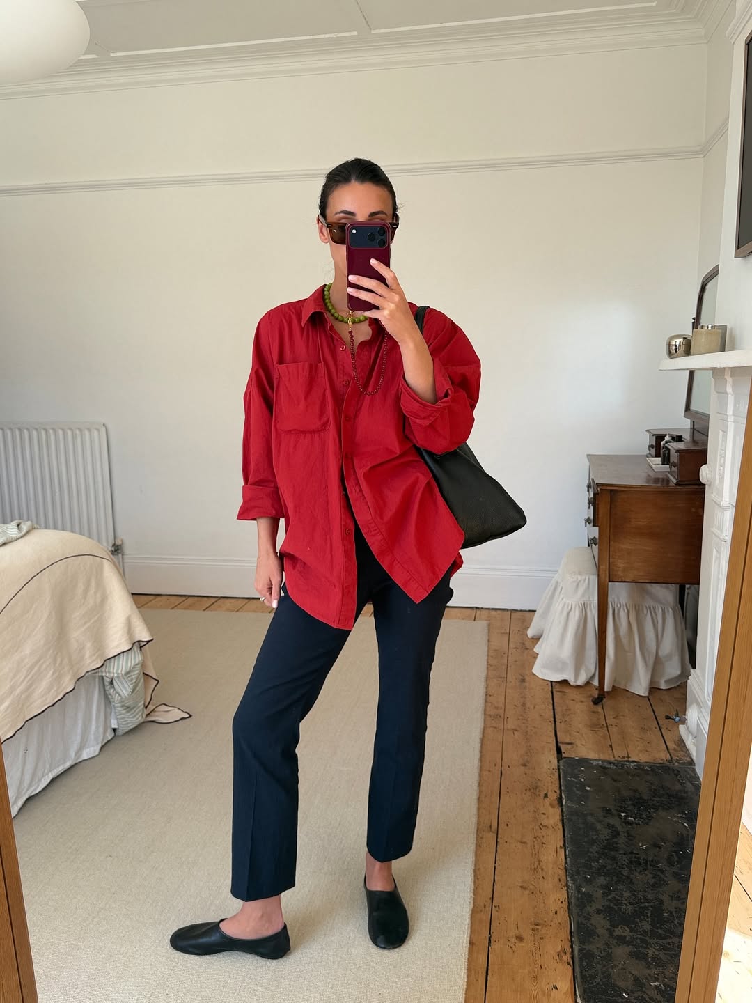 Influencer Emily Wells wearing a red shirt and navy trousers.