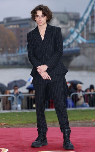 Timothée Chalamet's Wonka Press tour outfits including a pinstripe suit, purple suit, and black latex coat