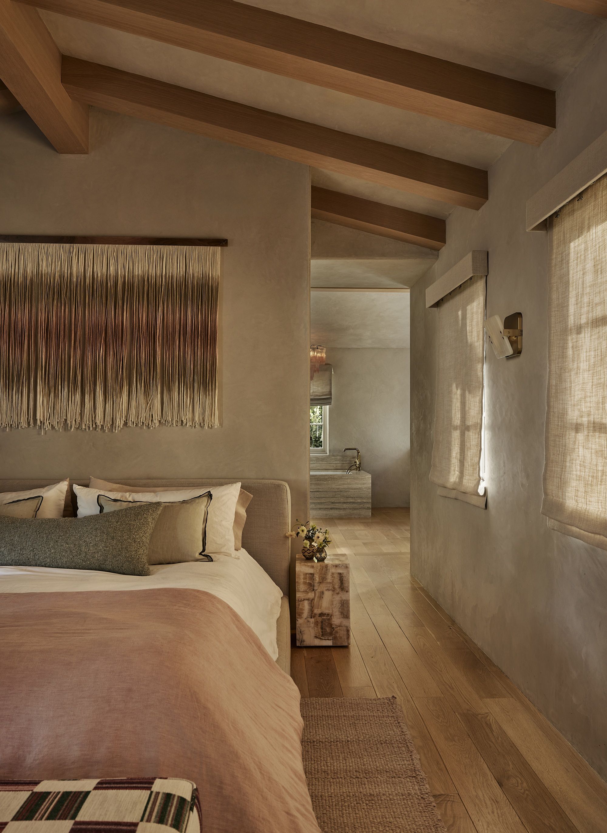 a rustic bedroom with limewash walls with a fringe wall art