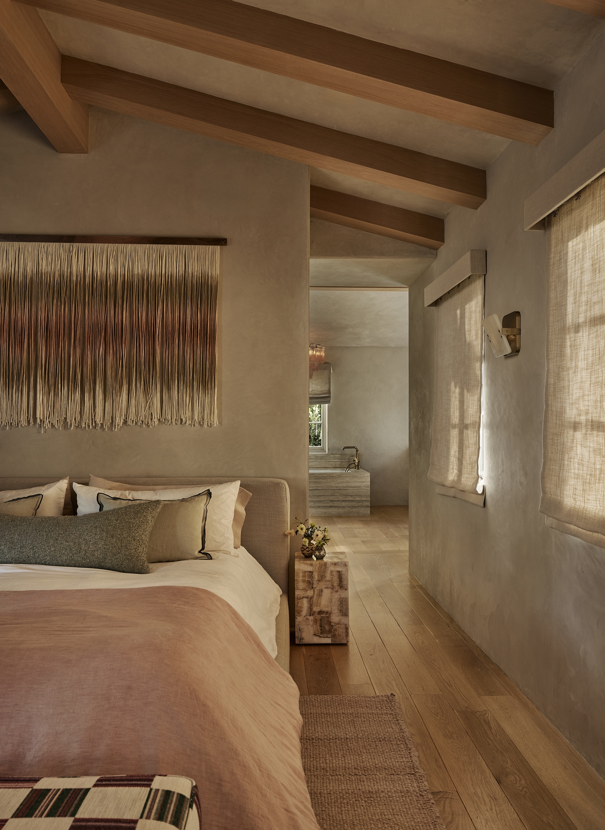 a rustic bedroom with limewash walls with a fringe wall art