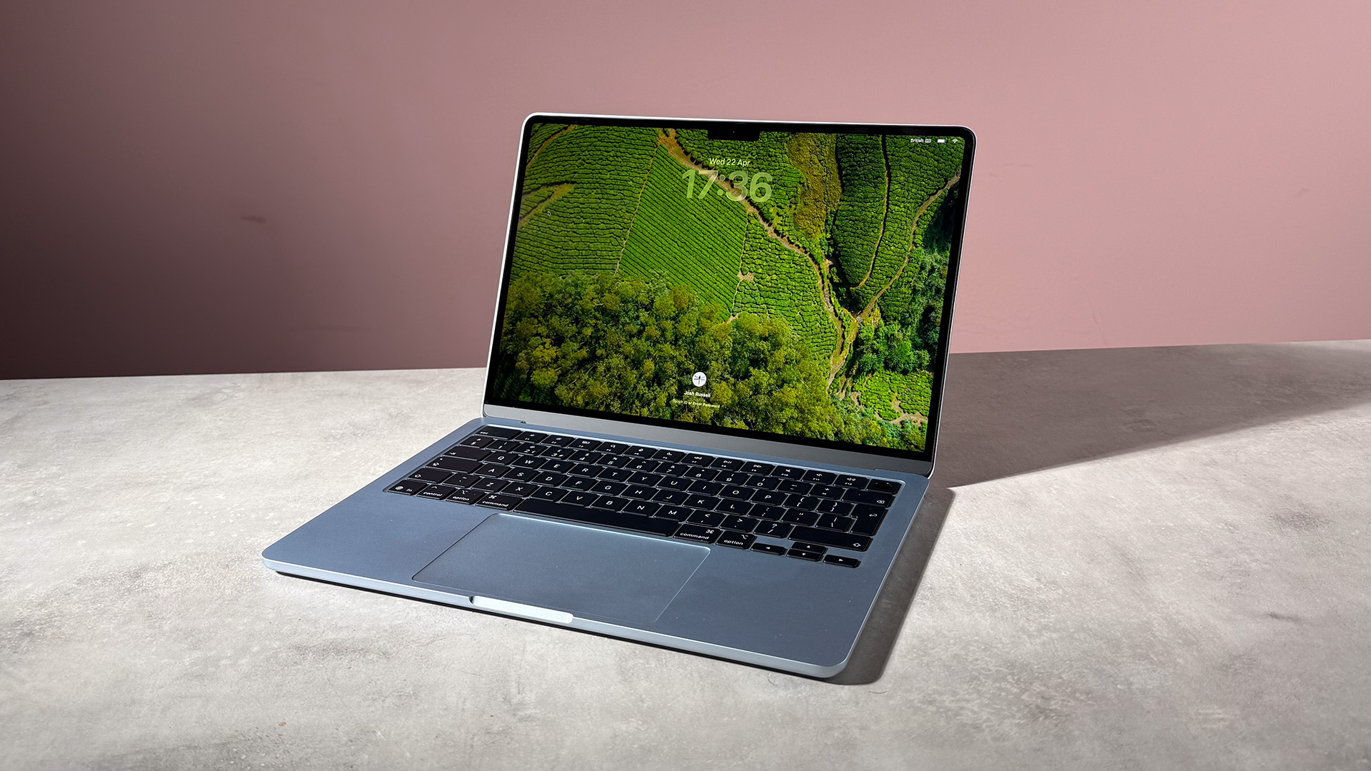 The MacBook Air M5 sky blue showing the lockscreen featuring rice fields from above.