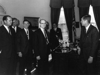 This 1961 photo shows Dr. William H. Pickering, (center) JPL director, presenting a Mariner spacecraft model to President John F. Kennedy, (right). NASA Administrator James Webb is standing directly behind the Mariner model.