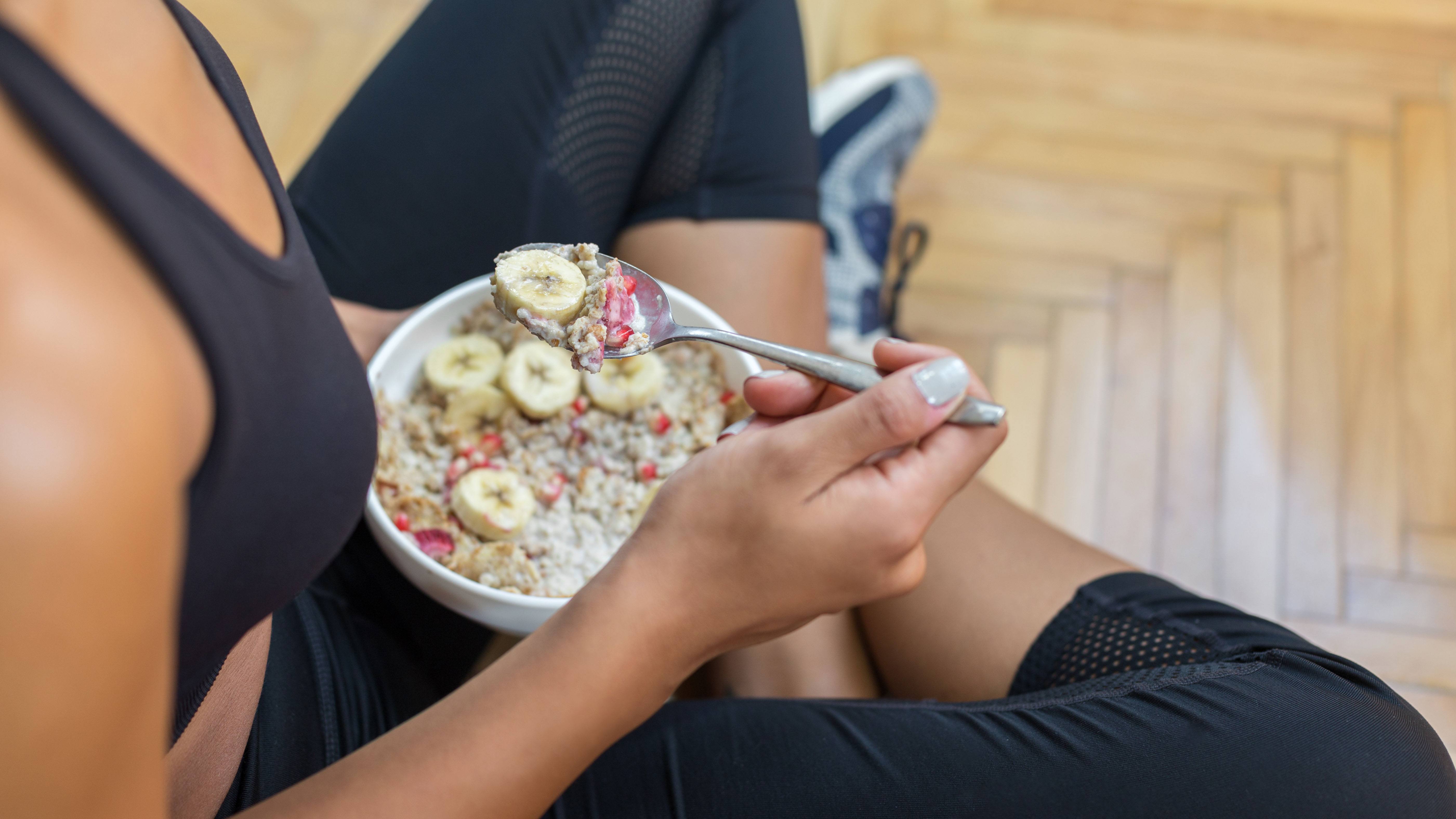 Woman in workout clothes eating oatmeal and berries