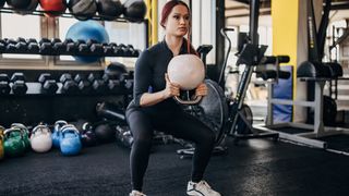 Woman doing goblet squat movement in gym