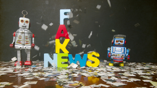 newspaper confetti comes down on the word FAKE NEWS with two retro robot toys on a wooden floor