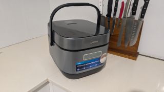 Midea 5L Induction Rice Cooker on a kitchen counter next to a knife block with knives