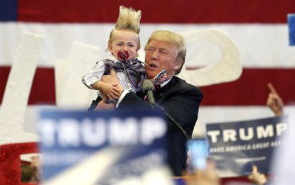 Donald Trump holds a young boy up during a rally.