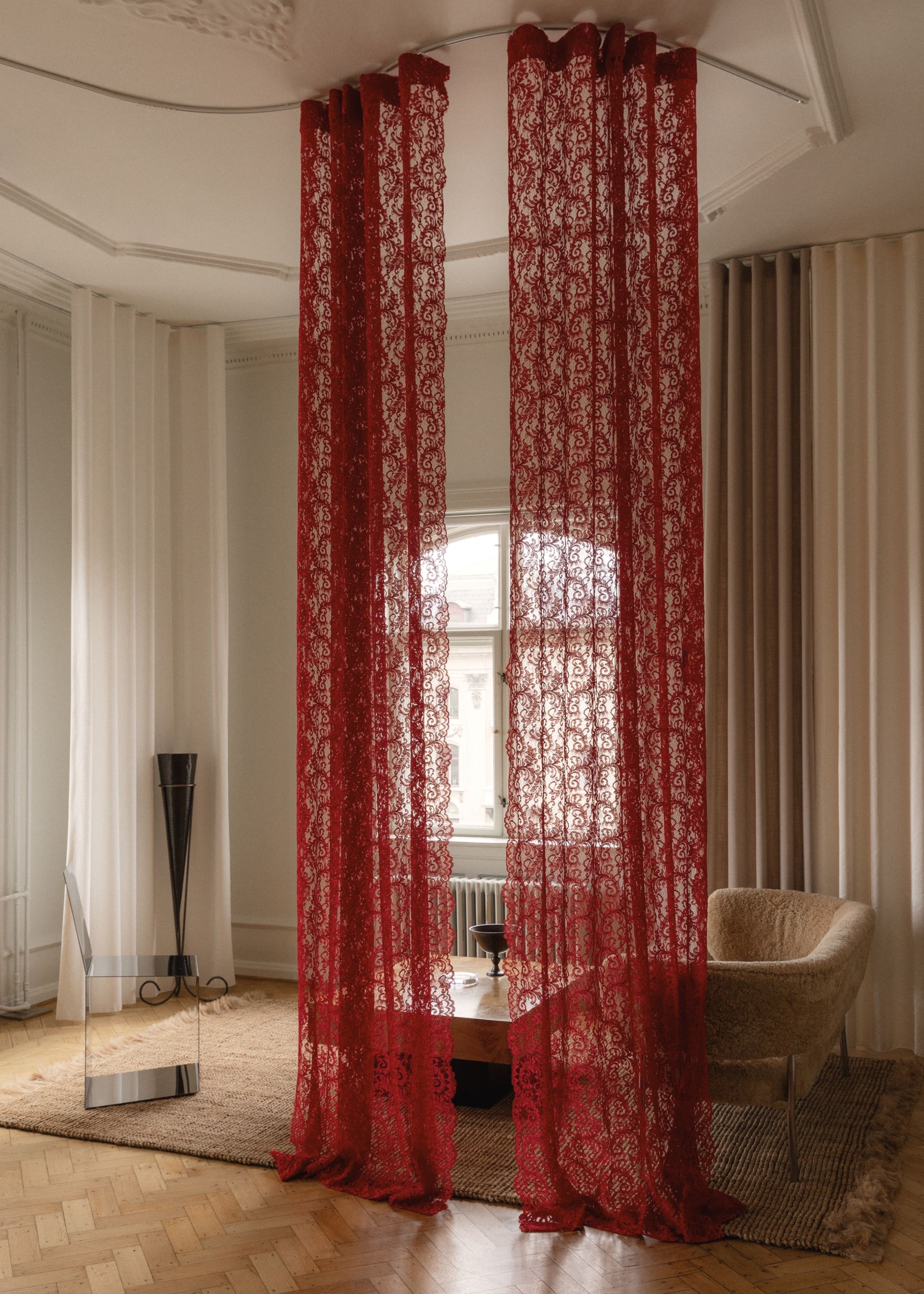 a minimalist room with a red lace curtain