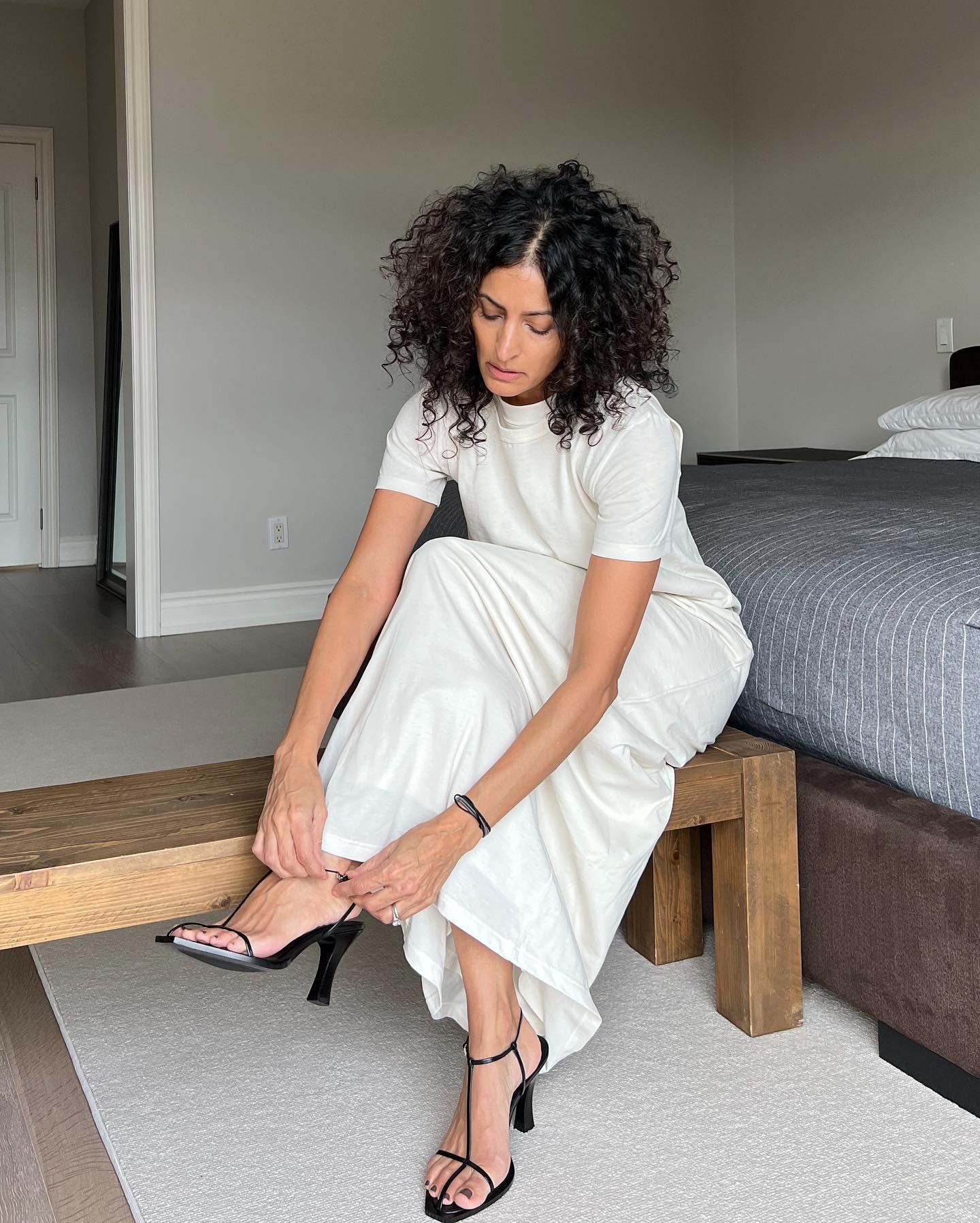 @neelam.ahooja wearing a white T-shirt dress and strappy heeled sandals.