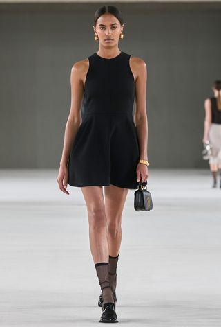 model wearing black dress with sheer socks and loafers