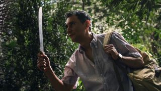 Manousos holding a machete walking through Durién Gap in Pluribus Episode 7