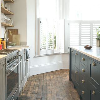 kitchen with reclaimed wood flooring dark grey island and white shutters on window