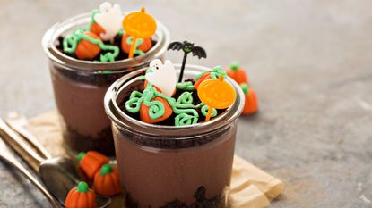 Glass pudding cups filled with chocolate pudding and topped with Halloween candies