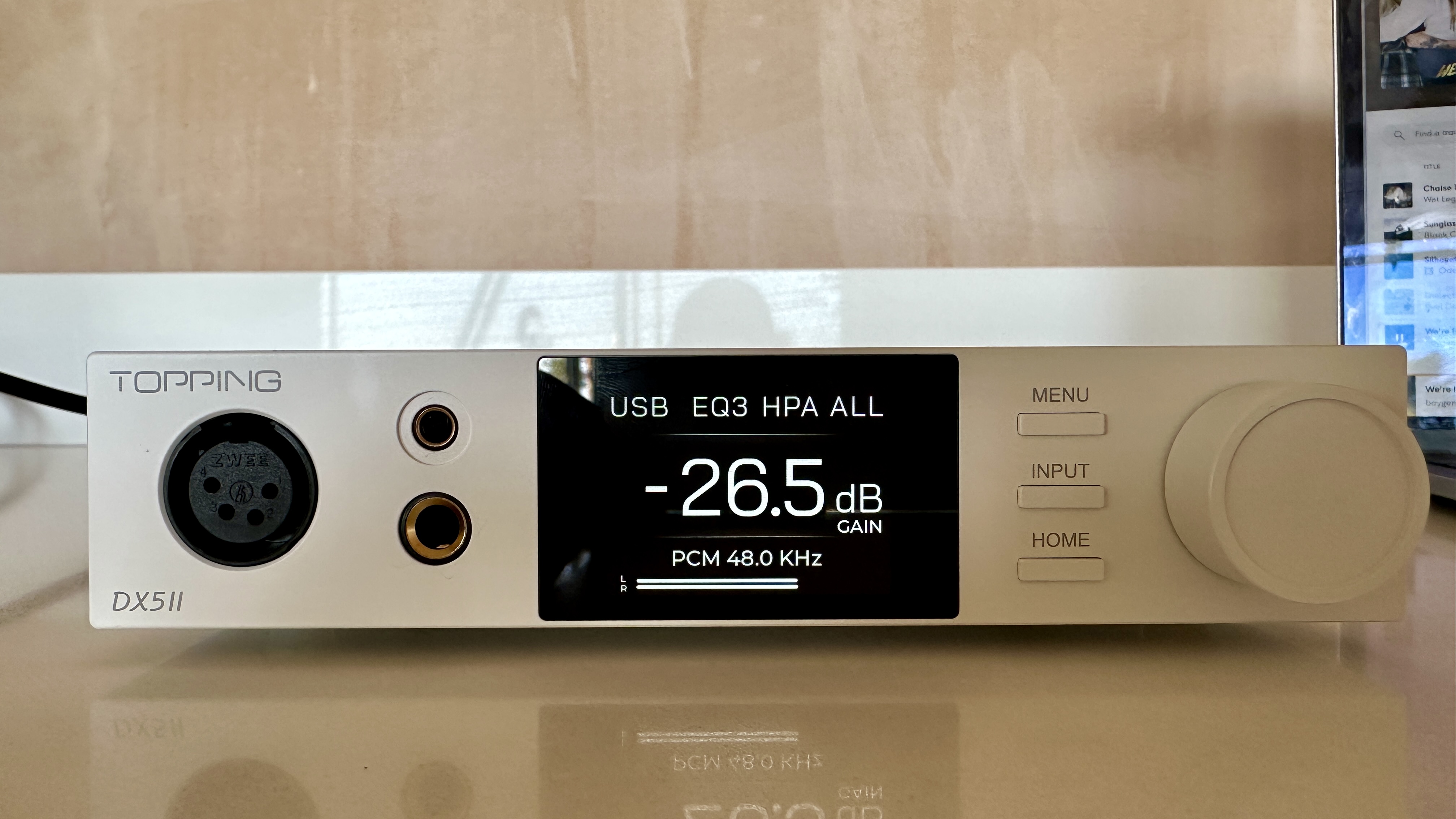 The Topping DX5 II on a light-wood table, showing the VU meter, ports and just-seen remote