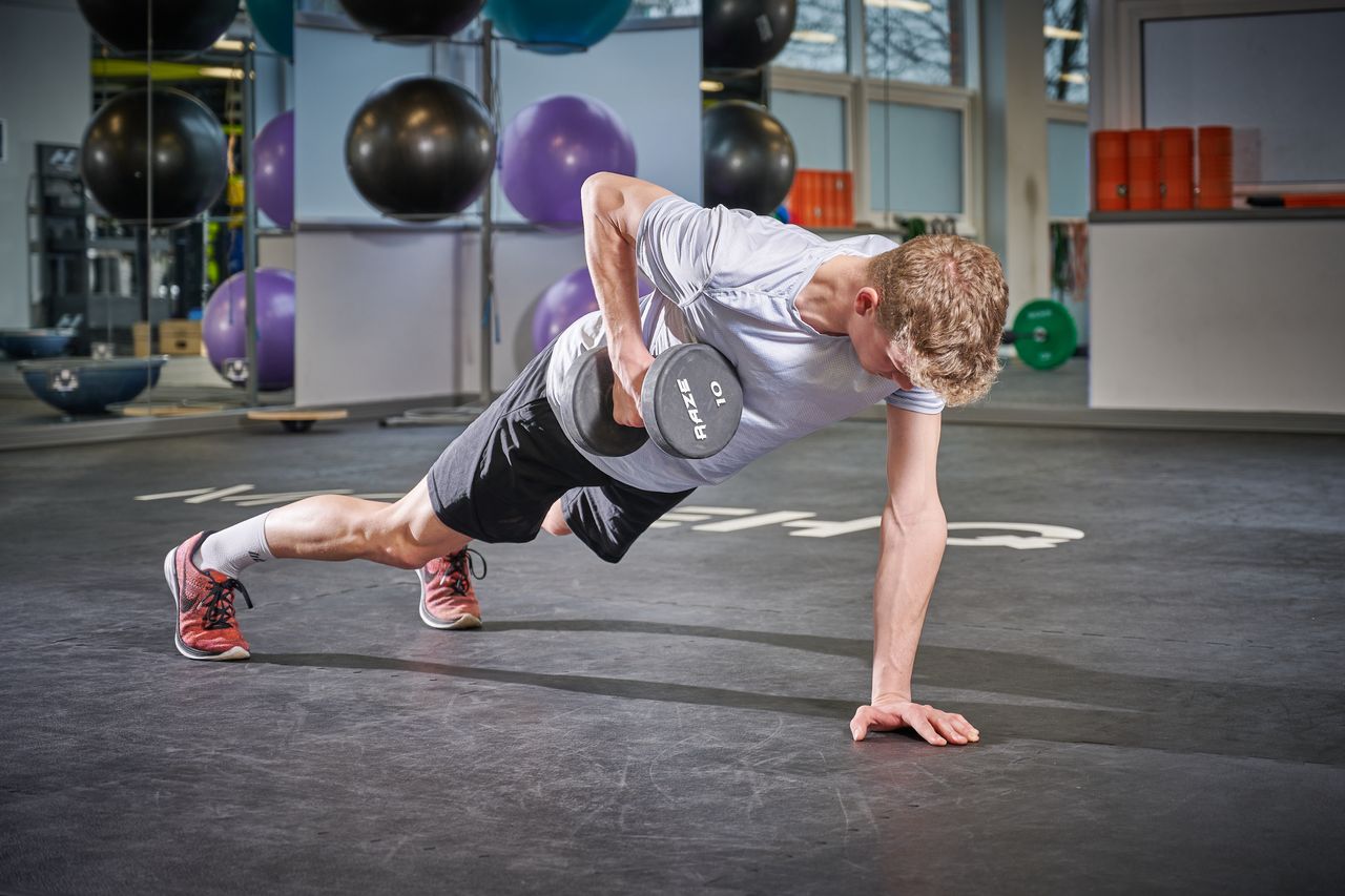 A man in the gym doing a plank row with dumbbell