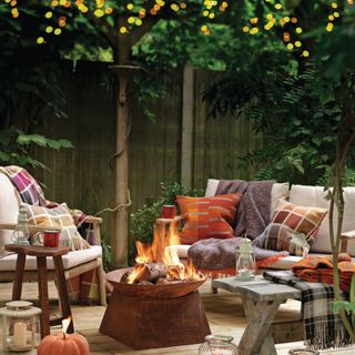 Cosy garden ideas: garden chairs around a firepit and surrounded by fairylights