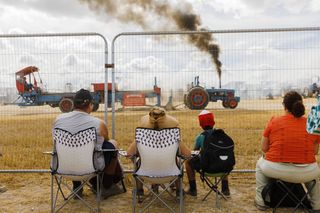 Martin Parr photo on show at Photo London 2023 showing seated spectators watching steam fair through a security fence