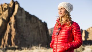 A hiker in the desert wearing an orange jacket and white hat