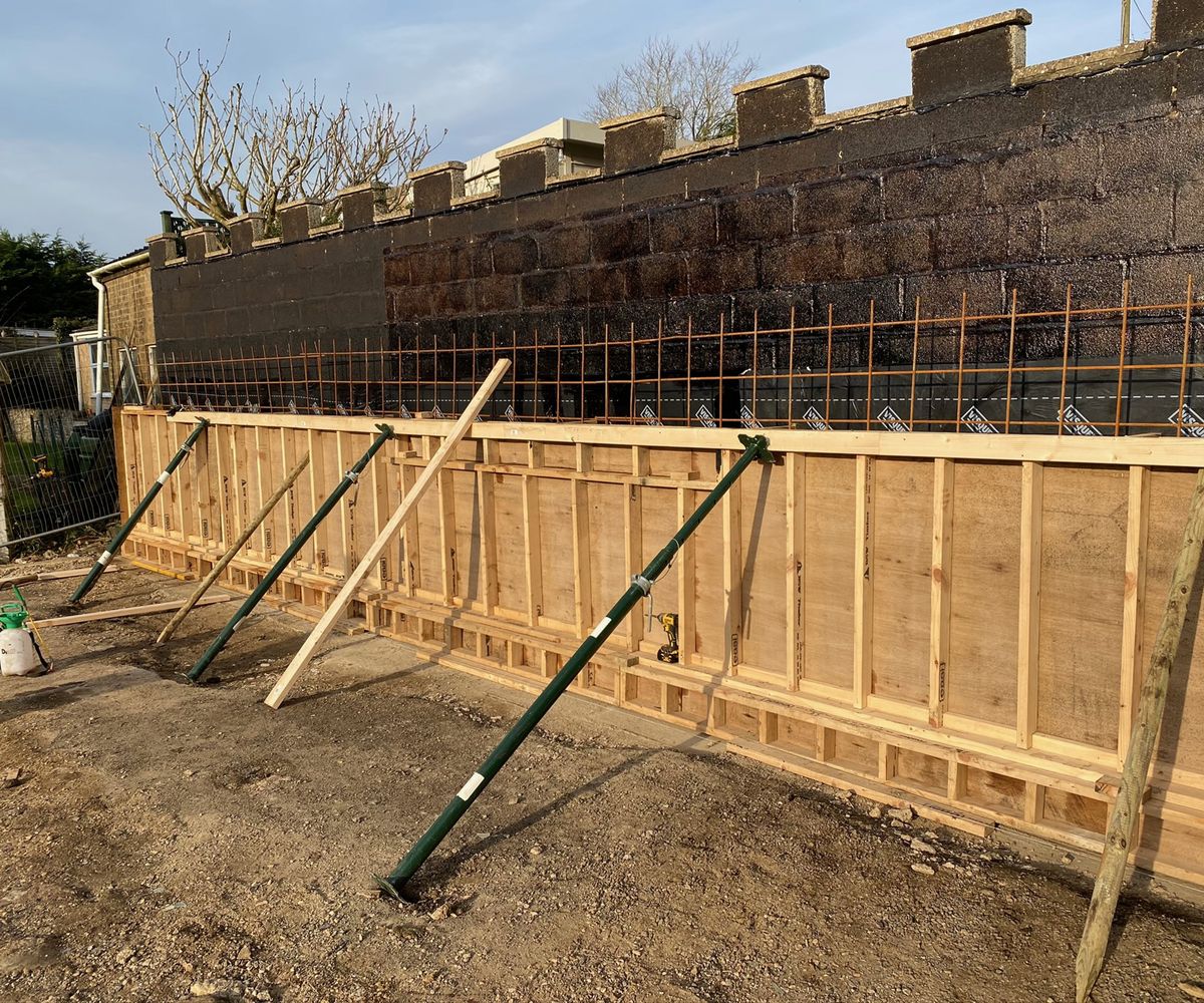 wooden planks holding stonework wall in place for an extension