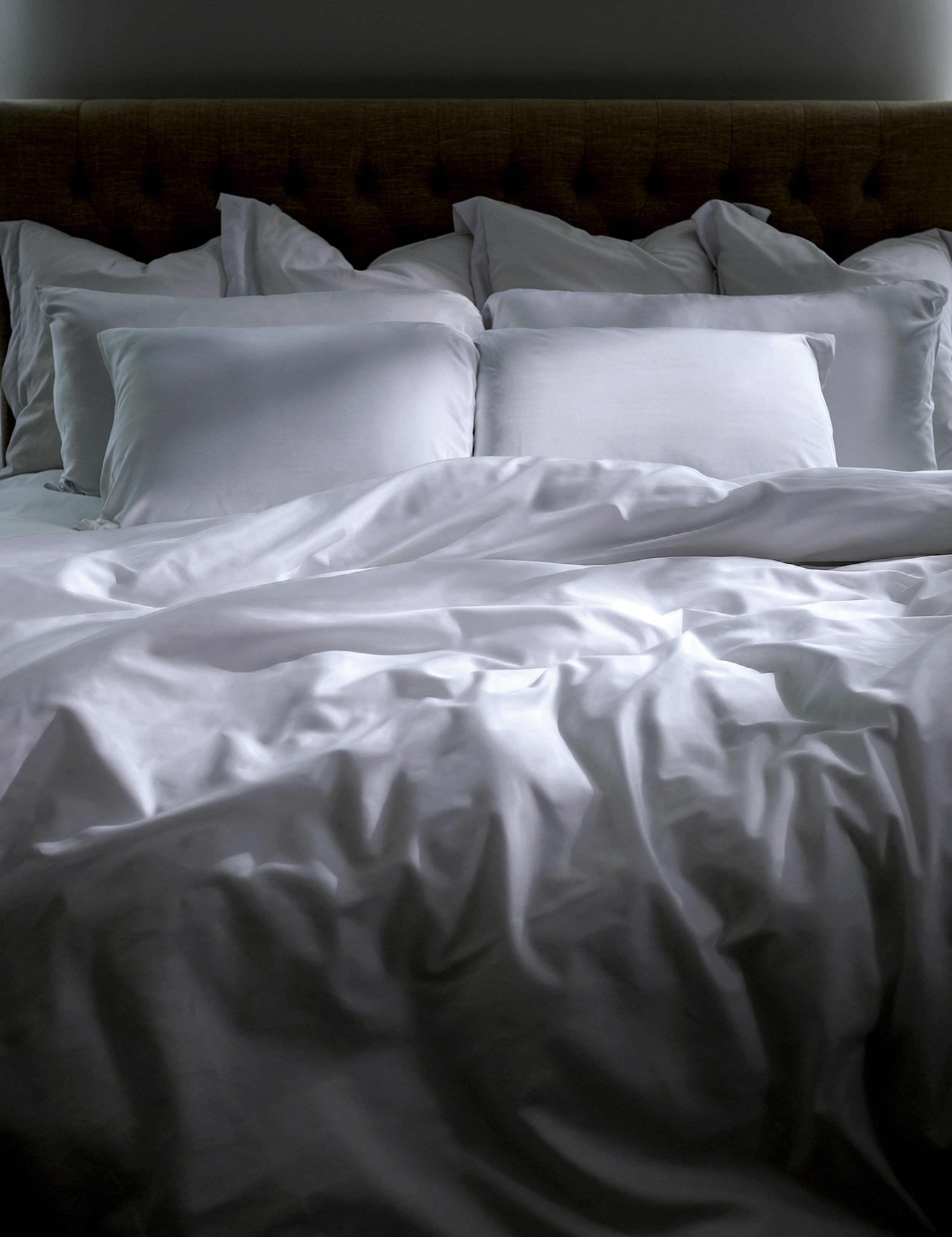 White bed sheets styled in a sunlit bedroom