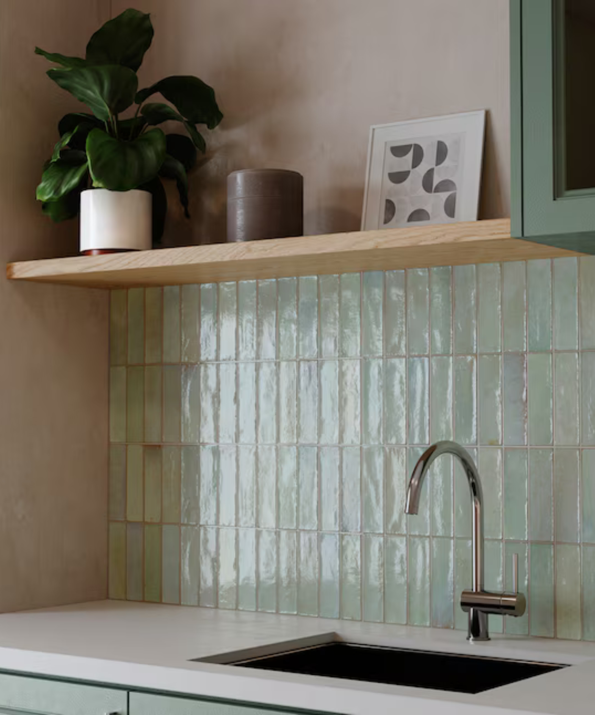 A kitchen corner with white countertops, a silver faucet, and sage green rectangle backsplash tiles