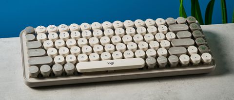 A photo of the Logitech Pop Keys keyboard on a stone surface against a blue background