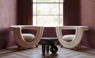 white curved armchairs against a pink wall