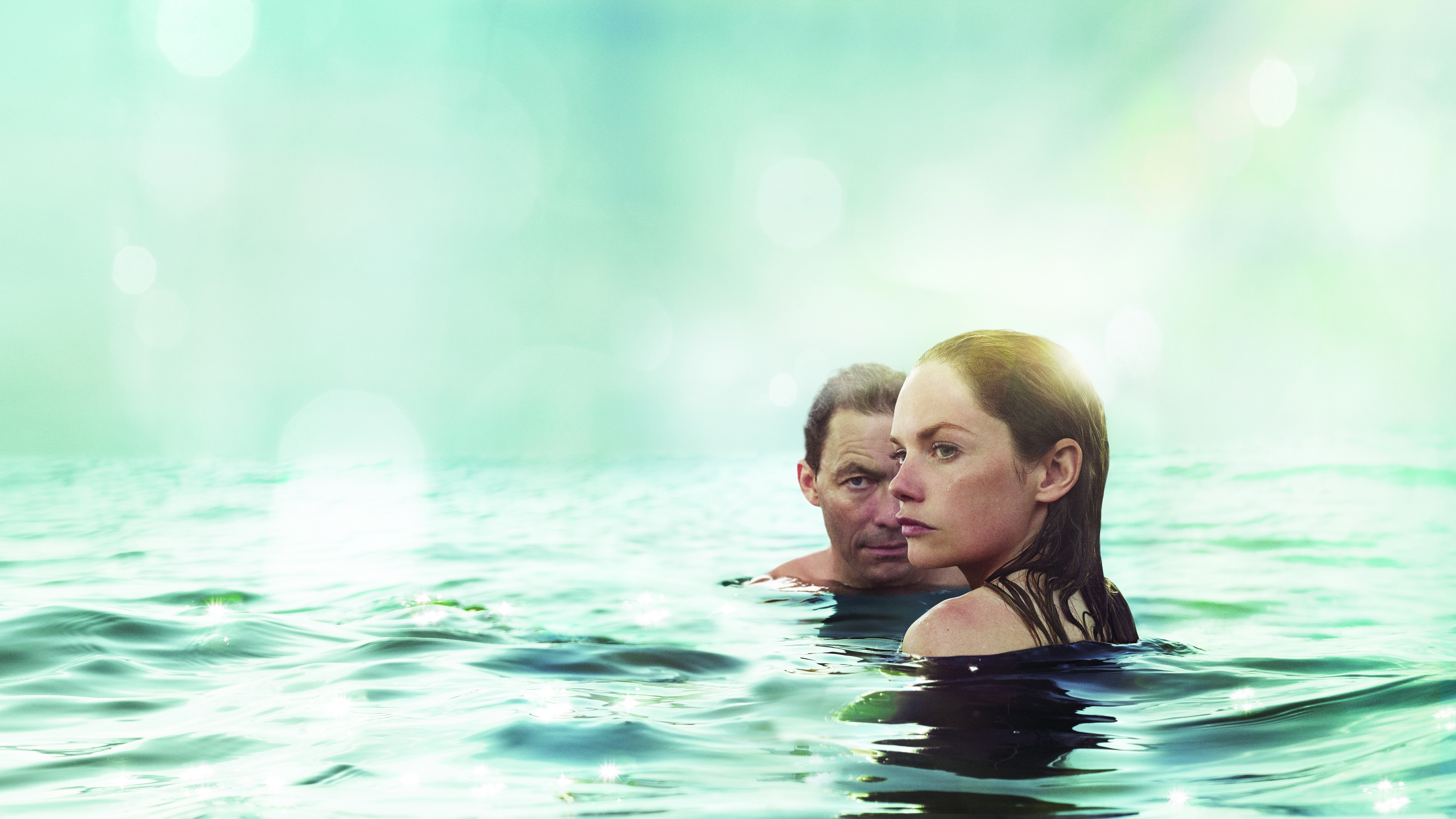 Dominic West (as Noah Solloway) and Ruth Wilson (as Alison Lockhart) with their head and shoulders only visible in the sea looking shady