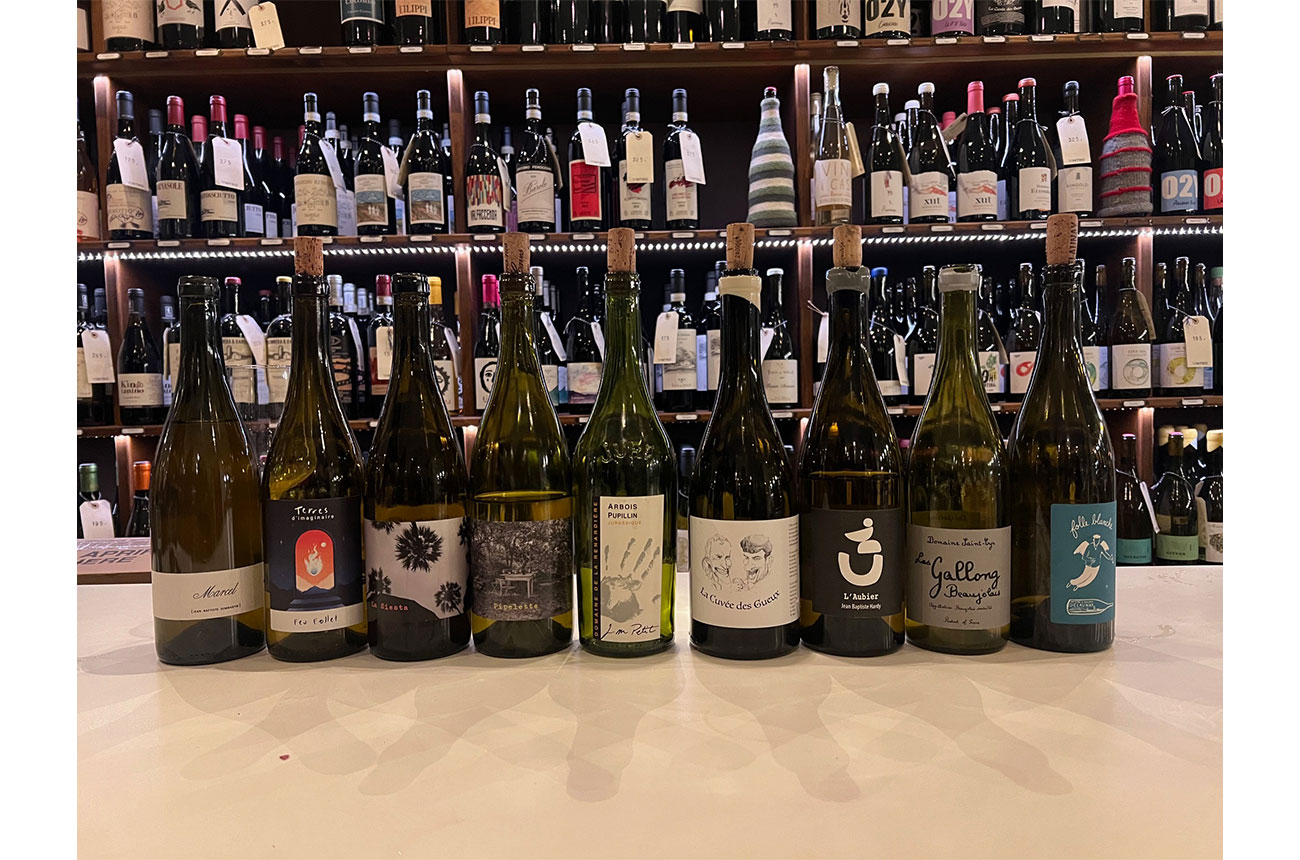 Bottles of wine on table with more bottles on shelves in background