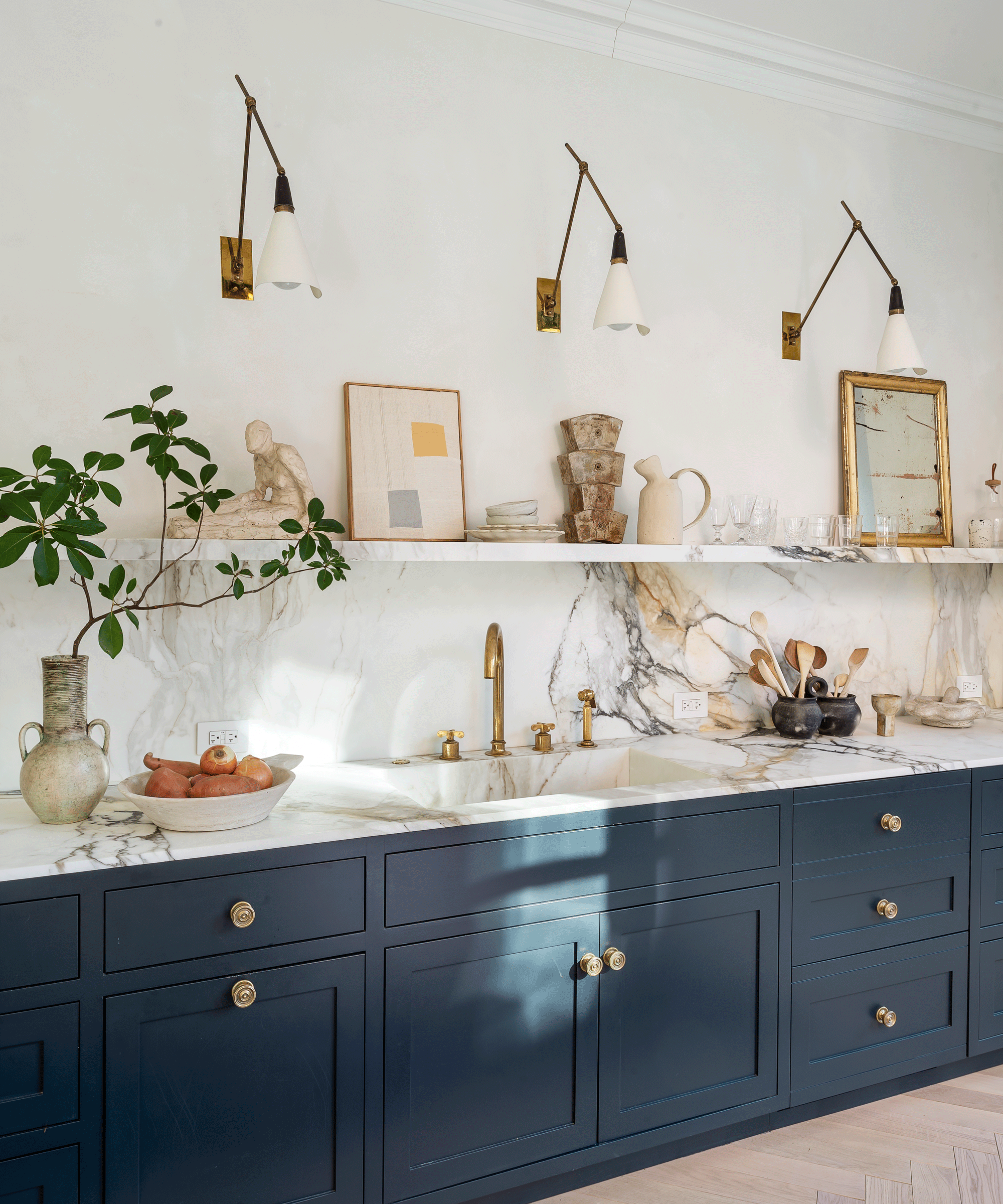 Marble veining A kitchen with blue cabinetry and a marble splashback and worktop