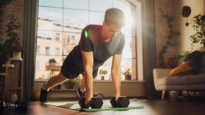 Man performing dumbbell renegade rows at home